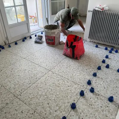 Carreleur PRBTP posant un carrelage terrazzo grand format avec croisillons autonivelants