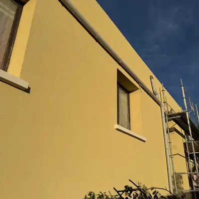 Façade rénovée avec un enduit jaune et des appuis de fenêtre repris