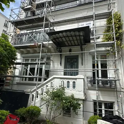 Façade en pierre de taille avec balcons en fer forgé, sous échafaudage de ravalement