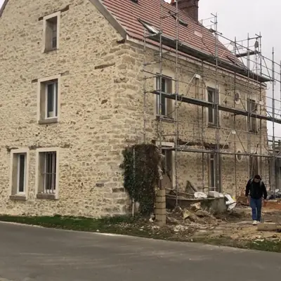 Longère en pierre apparente avec échafaudage en place pendant les travaux de façade