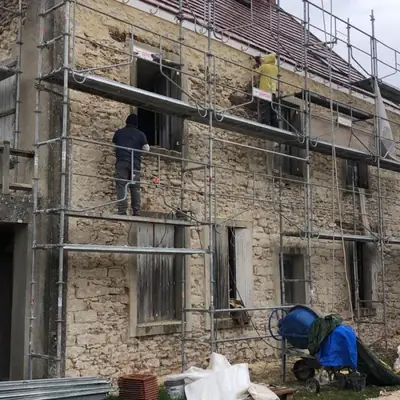 Deux compagnons PRBTP travaillant sur une façade en pierre depuis un échafaudage