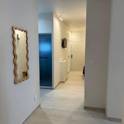 Couloir d'appartement rénové avec sol clair, éclairage encastré et peinture finie