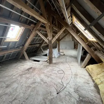 Combles avec charpente ancienne conservée et isolation en cours de mise en œuvre