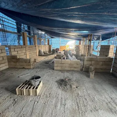 Murs en blocs béton en cours d'élévation sous une bâche de protection