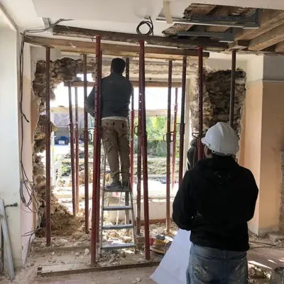 Compagnons PRBTP réalisant une ouverture dans un mur porteur avec étaiement et poutrelles