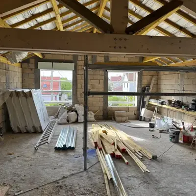 Intérieur d'une extension avec murs en blocs béton et charpente neuve apparente
