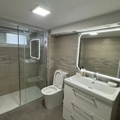 Salle de bains rénovée avec douche à l'italienne, meuble vasque et miroir rétroéclairé
