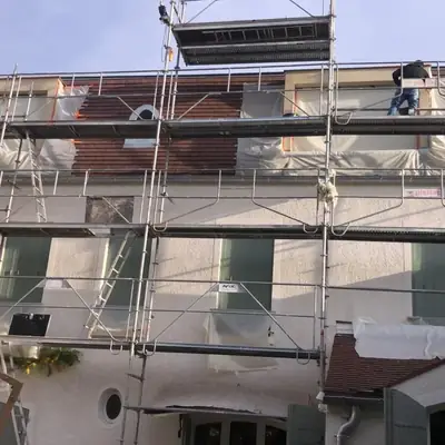 Partie basse d'une toiture en cours de reprise, avec protection de la façade