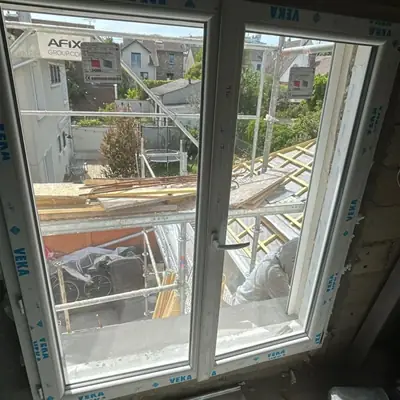 Fenêtre neuve posée, films de protection encore en place, chantier de toiture visible
