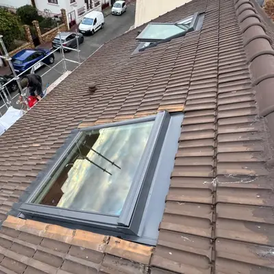 Deux fenêtres de toit installées sur une couverture en tuiles, raccords terminés